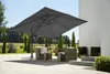 An outdoor patio scene with a large cantilever umbrella providing shade over a seating area. Produktbild-Vorschau