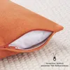 Close-up of an orange cushion with a partially opened zipper, revealing the white inner filling. The cushion is placed on a textured, light-colored surface. Anteprima dell’immagine prodotto