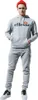 A man wearing a grey Ellesse tracksuit and a red beanie, posing against a white background. Podgląd zdjęcia produktu