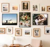 A collection of framed pictures displayed on a wall above a chair and a side table with a lamp. Produktbild-Vorschau