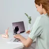 A woman is using a tablet with a keyboard attached, while a small pink fan sits on the desk next to her. Anteprima dell’immagine prodotto