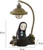 A figurine of a character from an anime, holding a small blue creature, standing next to a lamp post. Produktbild-Vorschau