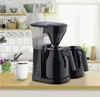 A black coffee maker with two carafes and a white mug of coffee on a wooden counter in a kitchen. Anteprima dell’immagine prodotto