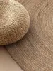 A close-up view of a round jute rug and a round jute pouf. Anteprima dell’immagine prodotto