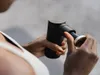 A person holding a black massage gun. Produktbild-Vorschau