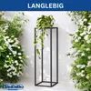 A black metal plant stand with a potted plant on it, surrounded by white flowers and greenery. Produktbild-Vorschau