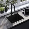 A modern kitchen sink with a black faucet, set against a window with white flowers. Náhled obrázku produktu