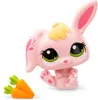 A pink toy bunny with yellow hair and green eyes sits next to two toy carrots on a white background. Podgląd zdjęcia produktu