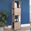 A tall, narrow, rotating shelving unit filled with books and binders, placed next to a large potted plant against a blue wall. Náhled obrázku produktu