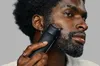 A man is trimming his beard with a black electric trimmer. Produktbild-Vorschau