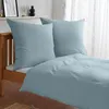 A neatly made bed with light blue bedding and pillows. Produktbild-Vorschau
