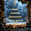 A Christmas tree-shaped window decoration with warm white lights and a star on top, set against a snowy window view. Voir les images du produit
