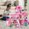 A young girl plays with a large pink dollhouse in a living room. Voir les images du produit