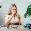 A young girl is working on a circuit board with wires and electronic components on a wooden table. Anteprima dell’immagine prodotto