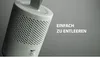 A close-up, angled shot of a white dehumidifier with a perforated exterior, set against a plain gray background. Text is overlaid on the right side of the image. Produktbild-Vorschau