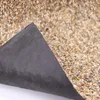 A close-up view of a piece of landscape fabric with a gravel-like texture on one side and a black woven fabric on the other, with a corner peeled back. Produktbild-Vorschau