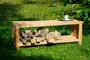 A wooden garden bench with a storage compartment for firewood, placed outdoors on a grassy lawn. Produktbild-Vorschau