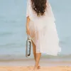 A woman walks on a beach holding a water bottle. Produktbild-Vorschau
