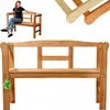 A woman is sitting on a wooden garden bench. The bench is made of light-colored wood and has a slatted backrest and armrests. The woman is wearing a black t-shirt and blue jeans. She is smiling and looking to the side. The bench is shown from the front and Produktbild-Vorschau