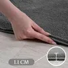 A hand is shown pressing down on the edge of a gray rug, with a close-up inset showing the rug's thickness. Podgląd zdjęcia produktu