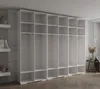 A large, white modular storage unit with multiple compartments and hanging rods, set against a light gray textured wall and a wooden floor. Produktbild-Vorschau
