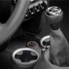 A close-up view of a car's interior, focusing on the gear shift, cup holders, and a power button. Anteprima dell’immagine prodotto