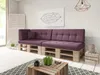A modern living room with a purple pallet sofa, a wooden coffee table, and a geometric artwork on the wall. Produktbild-Vorschau