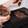 A person is pouring coffee beans into a coffee machine. Produktbild-Vorschau