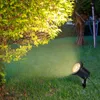 A black LED garden spotlight illuminates a grassy lawn and the leaves of a bush. Náhled obrázku produktu