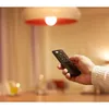 A hand holding a remote control pointing towards a smart light bulb. Voir les images du produit
