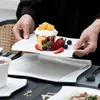 A person is holding a plate with a cupcake and fruits, presenting it over another plate. Náhled obrázku produktu