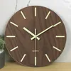 A close-up shot of a wooden wall clock with luminous hour markers and hands. Produktbild-Vorschau