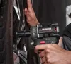 A person is using a cordless impact wrench to tighten a lug nut on a car wheel. Produktbild-Vorschau