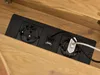 A close-up view of a black power strip with two European outlets and two USB ports, embedded in a wooden surface. Voir les images du produit