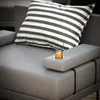 A close-up of a grey outdoor sofa with a striped cushion and a glass of orange juice on the armrest. Podgląd zdjęcia produktu