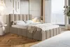 A bedroom scene featuring a bed with a headboard and frame upholstered in bouclé fabric, set against a wall with decorative paneling and a large window overlooking a landscape. The room is furnished with a bedside table, lamp, and a rug. Náhled obrázku produktu