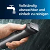 A hand holding a wet electric trimmer under running water, with text overlay indicating it is washable and easy to clean. Produktbild-Vorschau