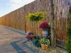 A garden scene with a bamboo fence, paving stones, and potted plants. Produktbild-Vorschau