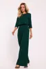 A woman is posing in a studio setting wearing a green jumpsuit. Anteprima dell’immagine prodotto