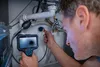A man is using a Bosch inspection camera to look into a drain pipe under a sink. Anteprima dell’immagine prodotto