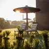Two chairs with cushions under a large umbrella in a garden at sunrise. Podgląd zdjęcia produktu
