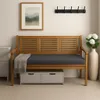 A wooden bench with a gray cushion and a gray blanket draped over it, placed in a room with a framed picture on the wall and a tall vase with white flowers. Produktbild-Vorschau