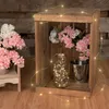 A wooden crate filled with flowers and decorative lights. Produktbild-Vorschau