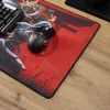 A gaming mouse and keyboard are placed on a large, red mousepad with artwork, resting on a wooden desk. Produktbild-Vorschau