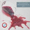 A glass of red wine is spilled on a white textured surface, demonstrating the waterproof nature of the product. A circular logo and text overlay are also present. Produktbild-Vorschau