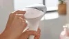 A person's hands are holding and operating a white and silver IPL hair removal device. Náhled obrázku produktu