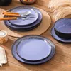 Geschirrset und Besteck auf hellem Holztisch Voir les images du produit