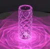A crystal diamond-shaped table lamp emitting pink light onto a surface. Produktbild-Vorschau