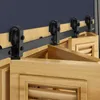 A close-up view of a sliding door hardware system mounted above wooden doors. Náhled obrázku produktu