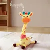Gelbes Plüsch-Giraffenspielzeug mit orangefarbenen Flecken und Schnauze, rotem Tuch und Musiknoten, die über seinem Kopf schweben Podgląd zdjęcia produktu